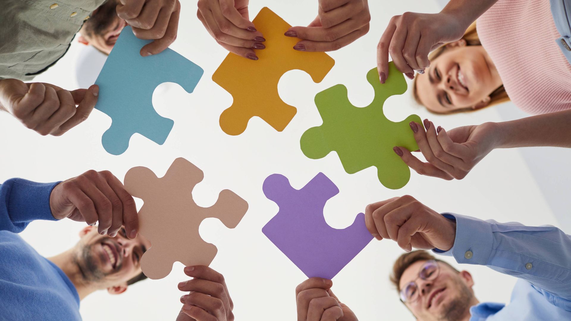 Image of team members holding pieces of a jigsaw puzzle