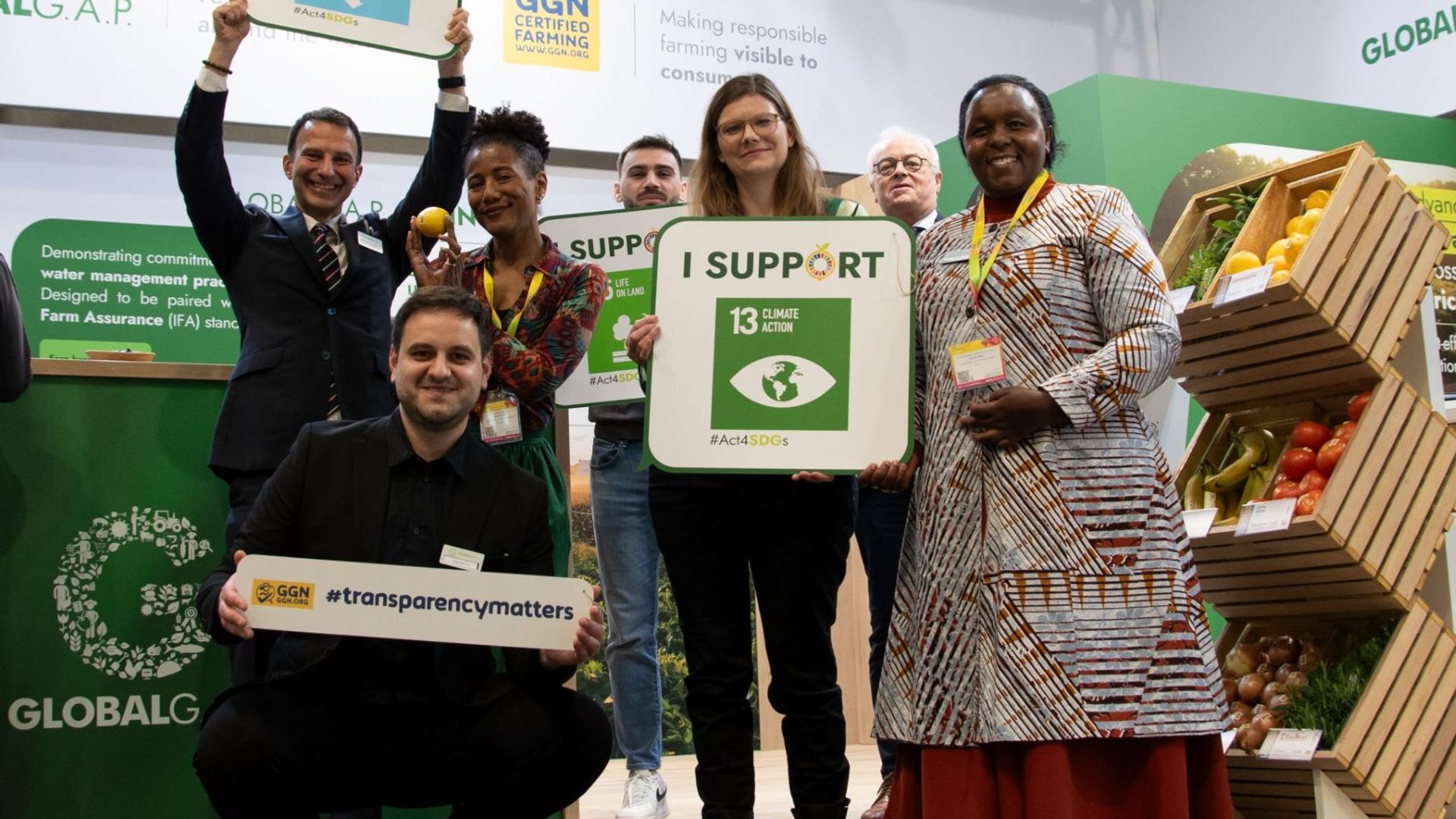 Stakeholders holding signs related to the UN Sustainable Development Goals at the GLOBALG.A.P. booth at Fruit Logistica 2024 in Berlin.
